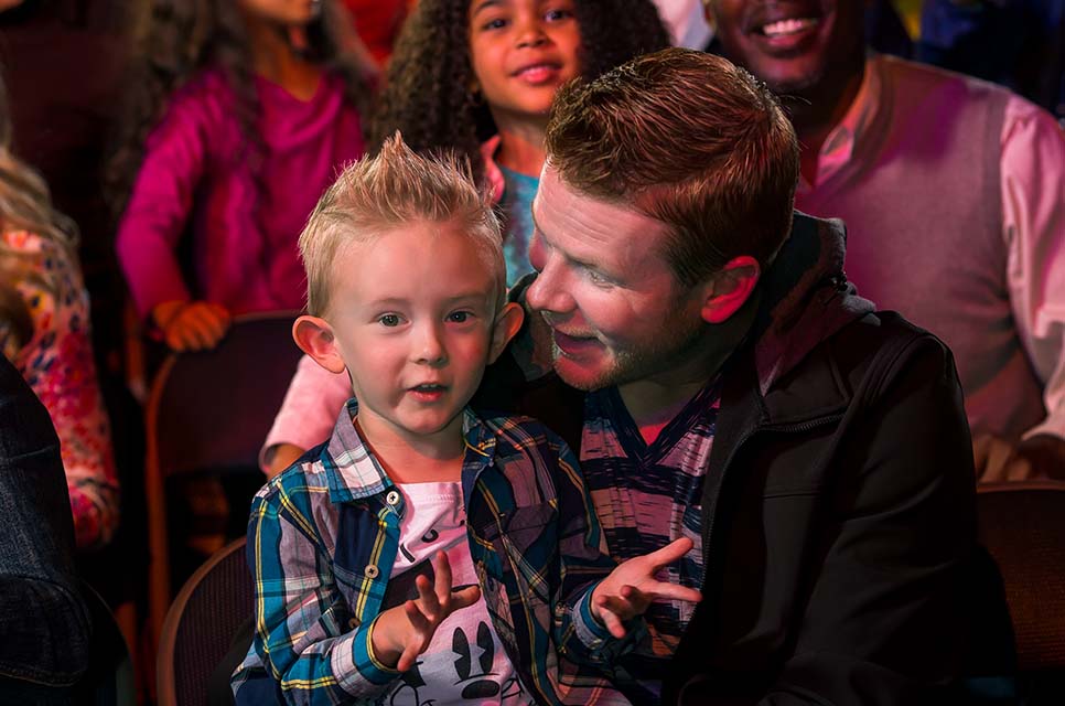 Vader en jong kind genieten samen van een live Feld Entertainment show